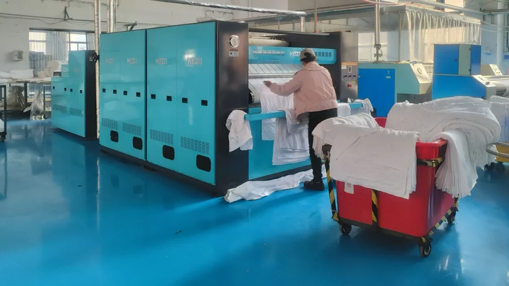Flatwork ironer and linen carts in a working commercial laundry